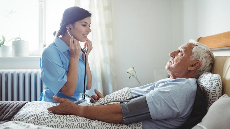 nurse caring for elderly resident in profiling bed