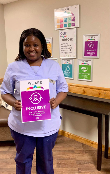 A smiling team member at Westerton Care Home holding their award for embodying the care home's values