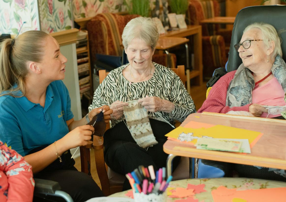 Elderly people knitting with care worker