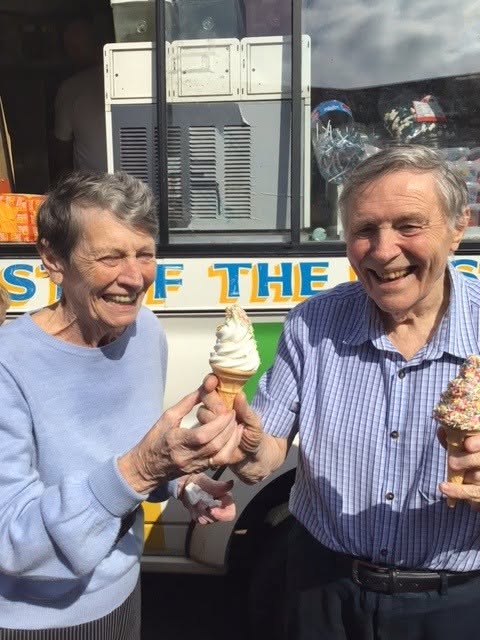 elderly couple holding ice creams and smiling in the sunshine