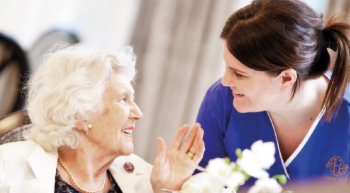 elderly woman smiling with a nurse in a care home